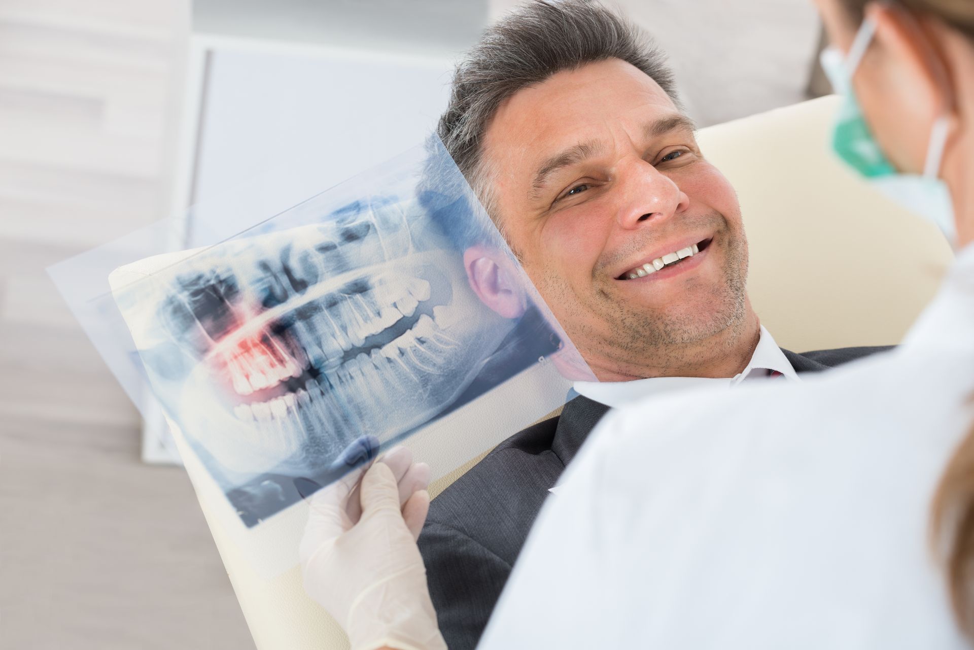 Dentist showing smiling patient an X-ray in a bright clinic