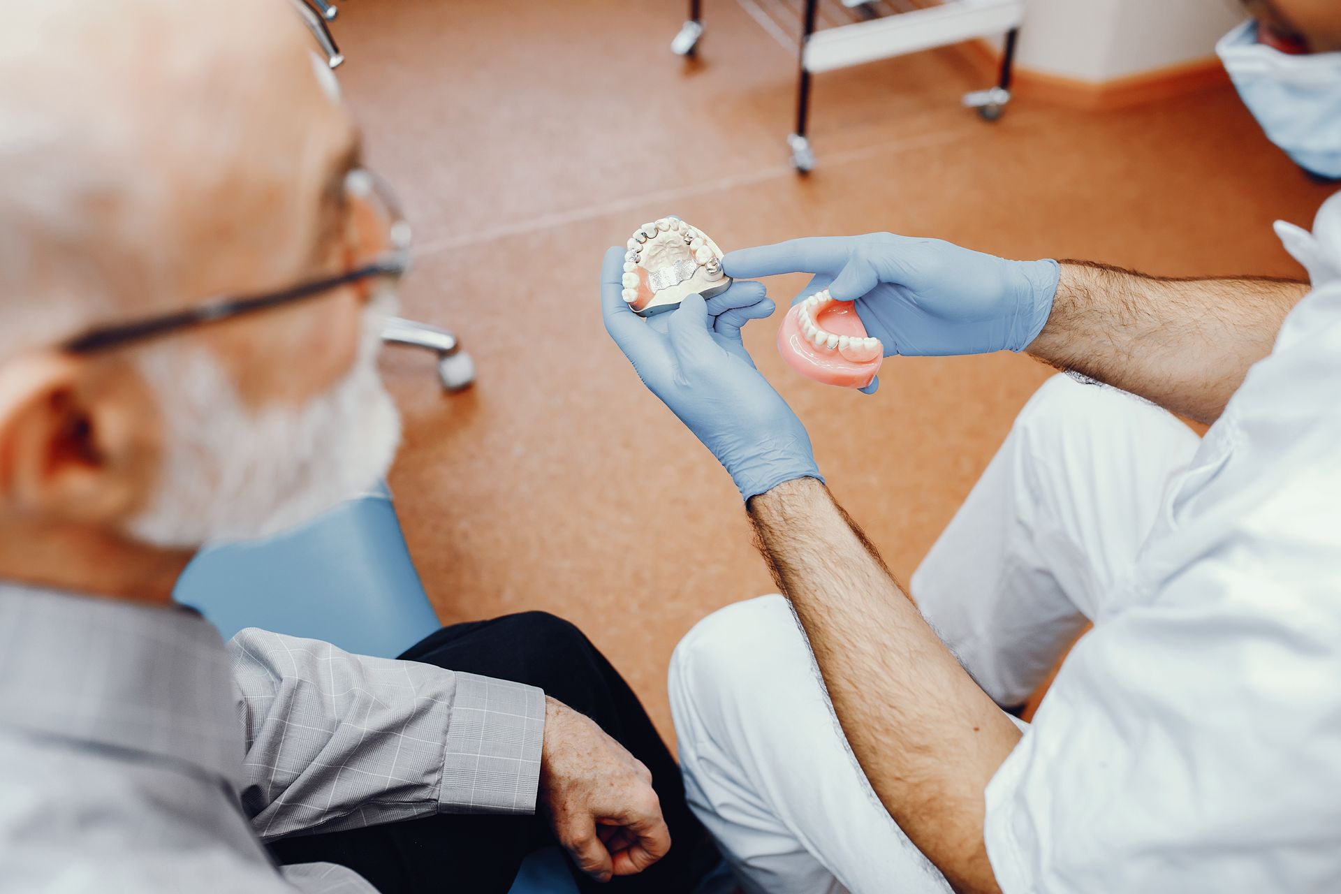 Dentist showing a dental implant model to a patient in a clinic