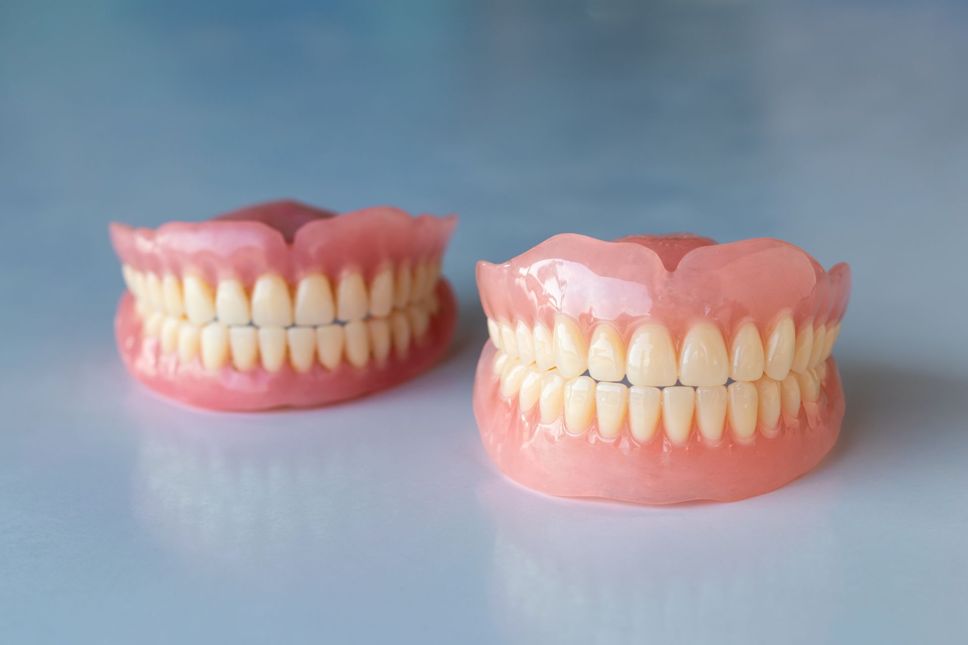 Two pink dental models showing upper and lower teeth on a light blue surface