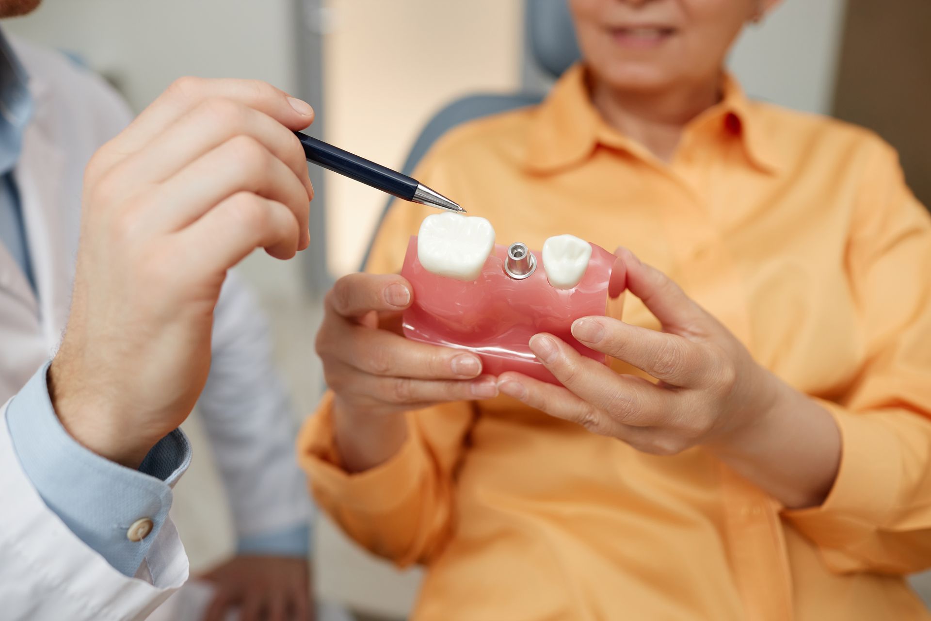 Hands holding a dental model while a brush points to the teeth during a demonstration