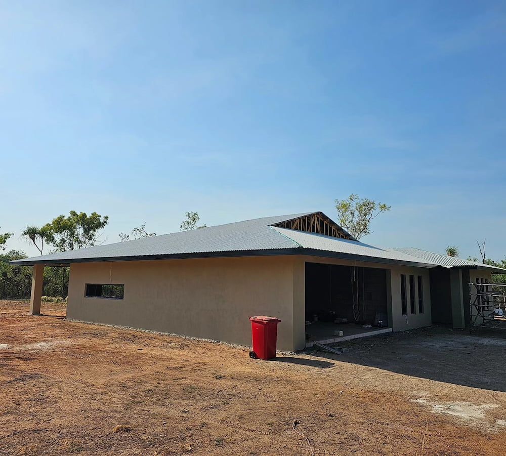 A Tan-coloured Building Under Construction With a Red Trash — KNG Roofing And Construction in Darwin, NT