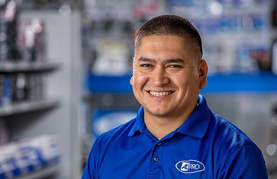 Smiling man in a blue polo shirt inside a retail store aisle