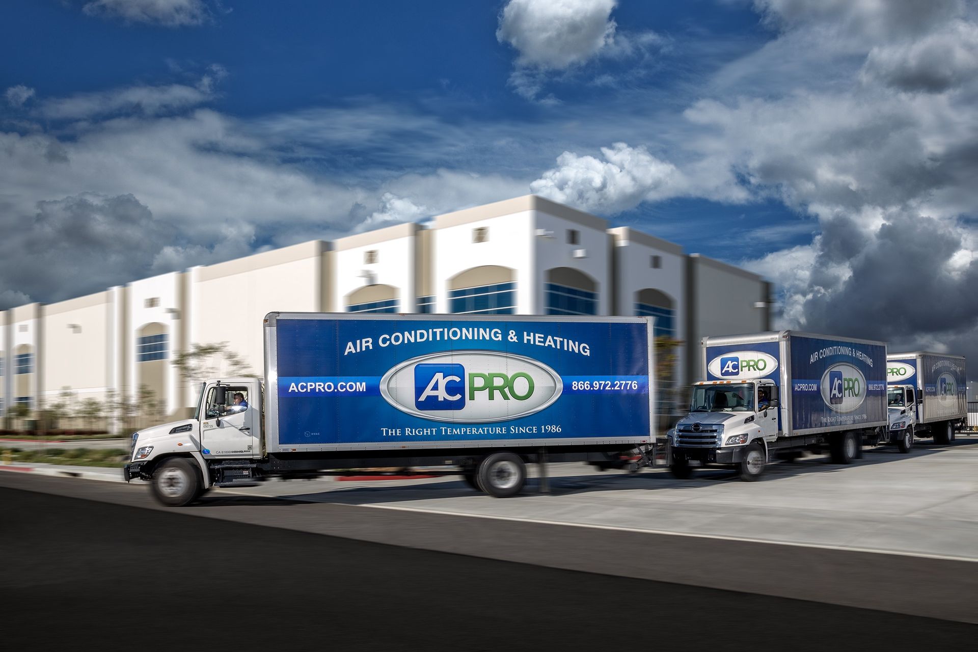 Delivery trucks parked outside AC Pro warehouse under a cloudy sky