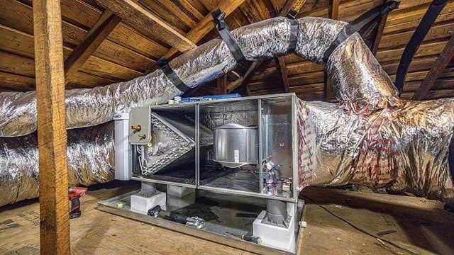HVAC unit in an attic with insulated ductwork.