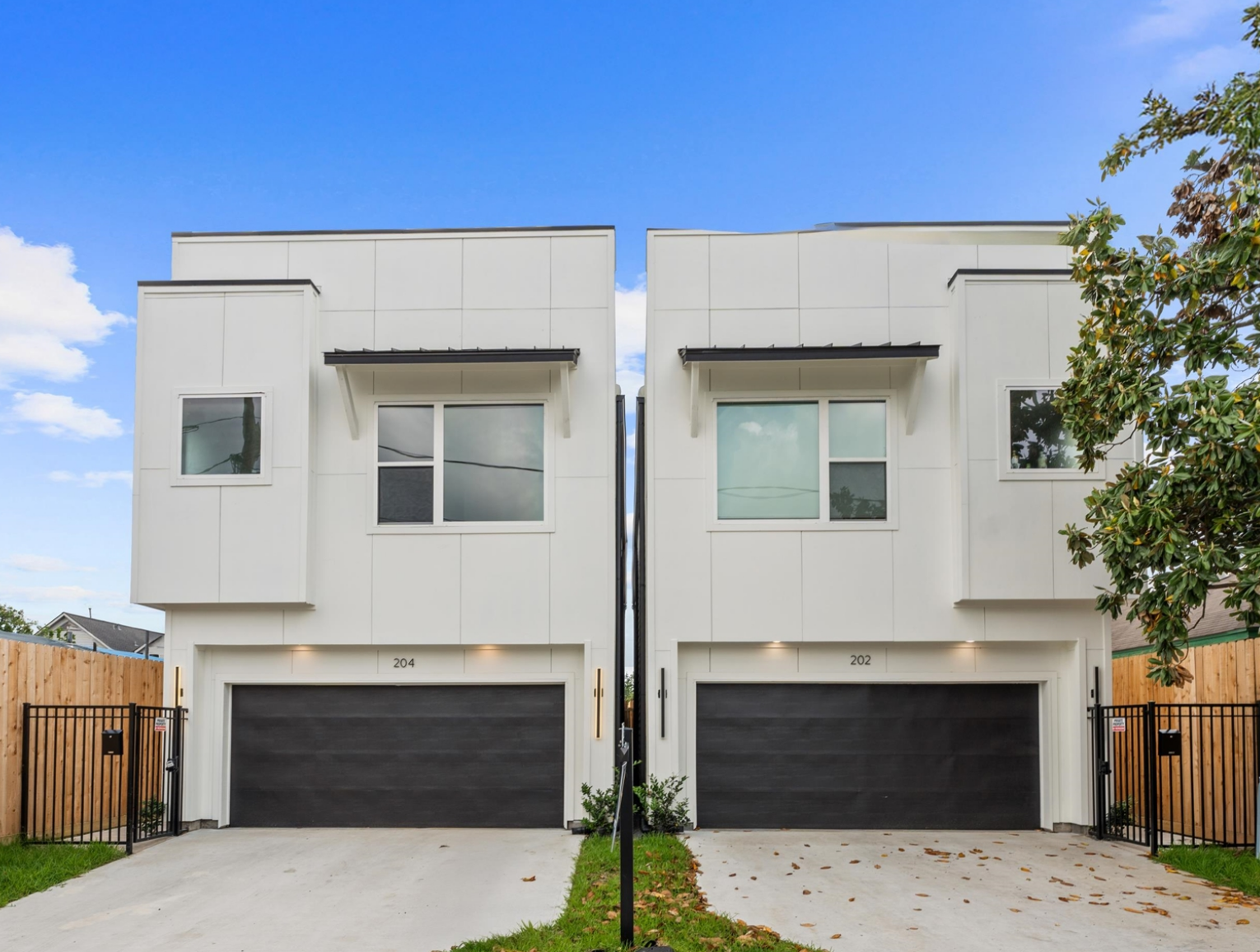 Two modern white townhomes with black garage doors; one available.