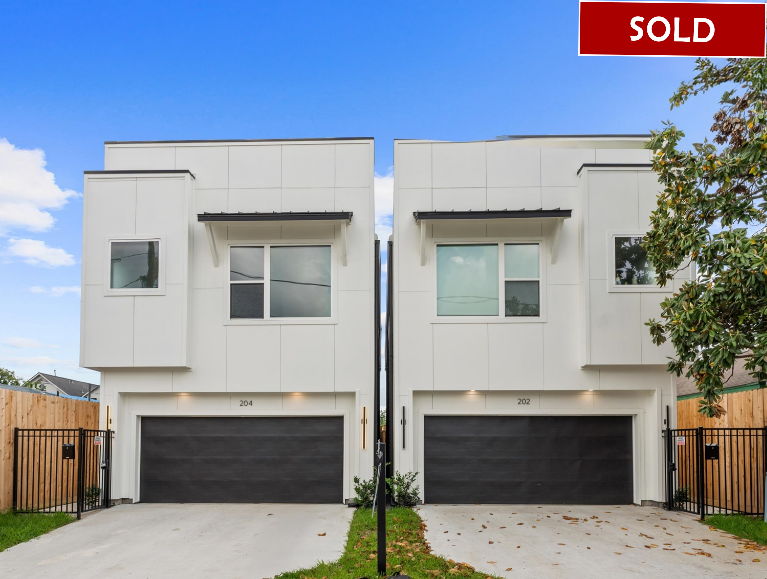 Two modern white townhomes with black garage doors; one available.