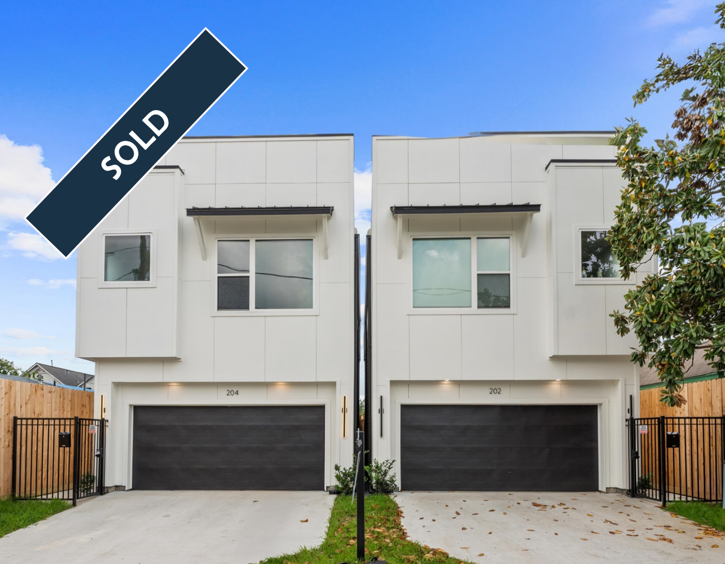 Two modern white townhomes with black garage doors; one available.