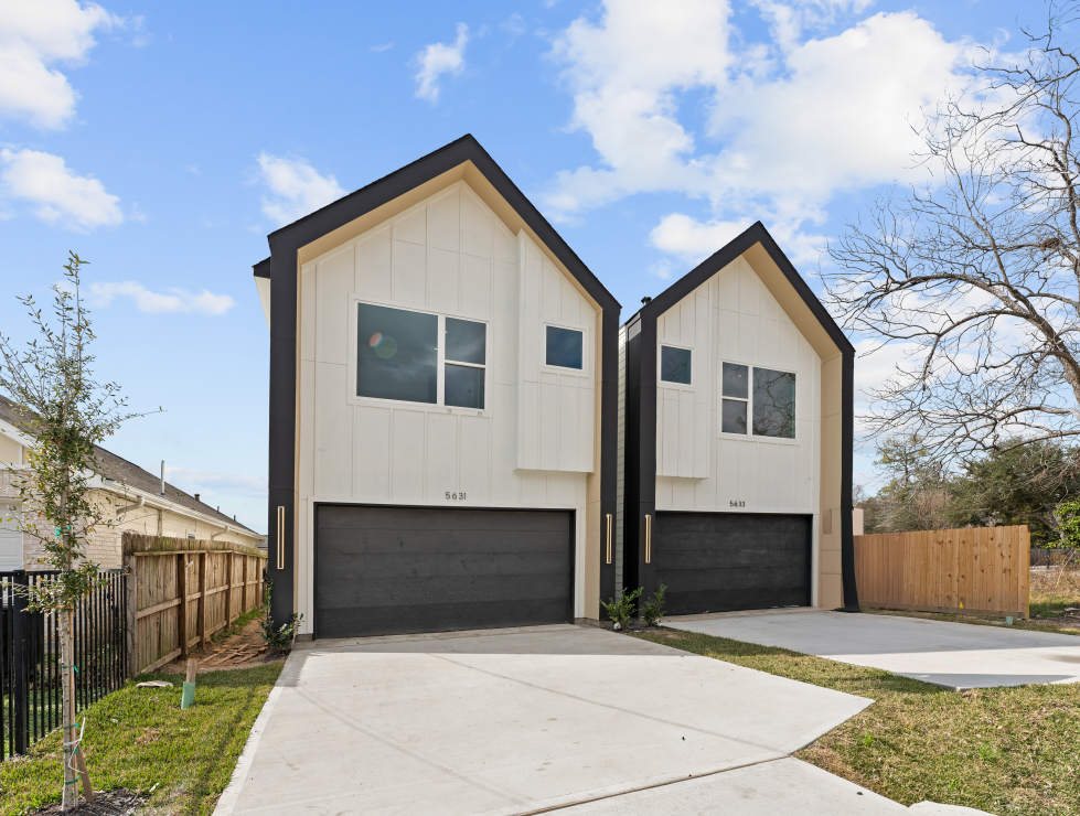Two modern white houses with black trim and garage doors, 