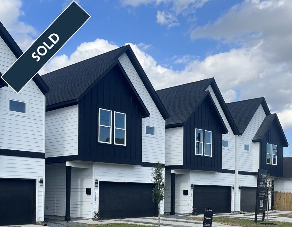 Row of modern townhouses with white siding, black accents, and a 