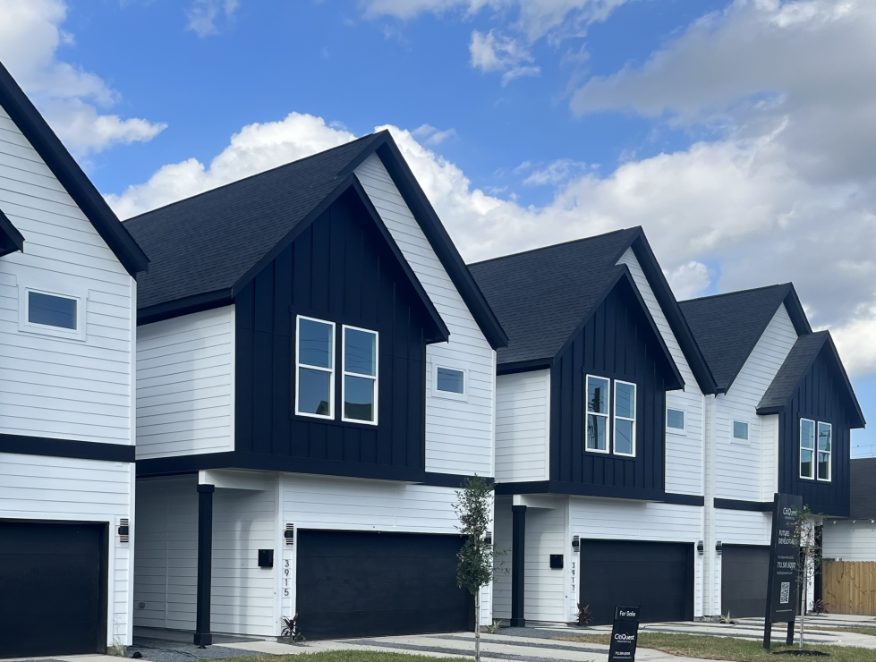Row of modern townhouses with white siding, black accents, and a 