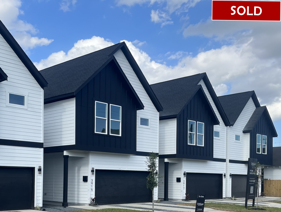 Row of modern townhouses with white siding, black accents, and a 