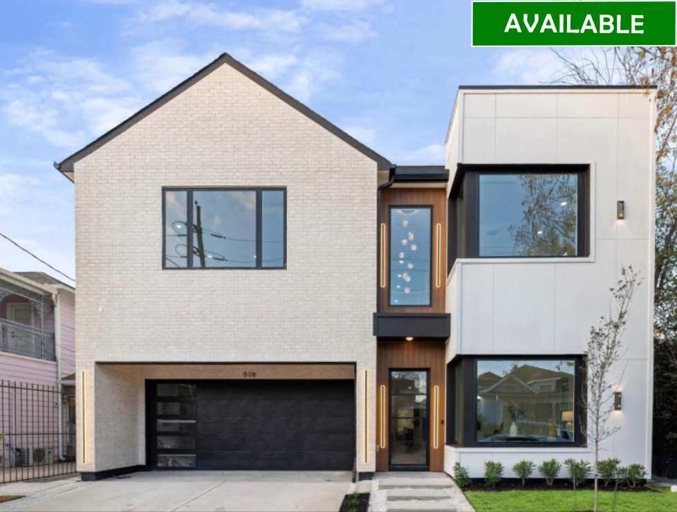 Modern white home under construction with black trim, windows, and garage door. Lush green lawn.