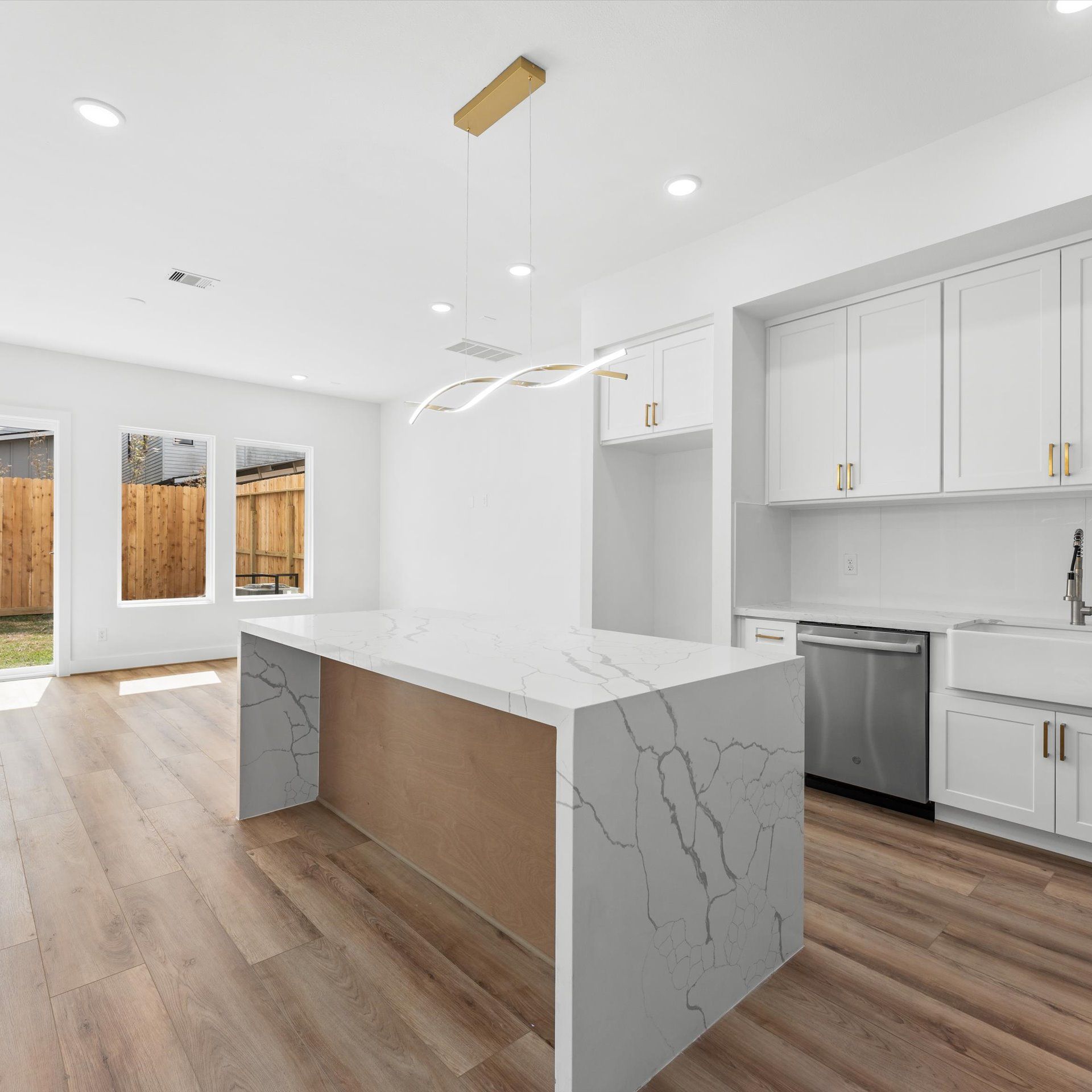 Modern kitchen with a large island, white cabinets, and wood flooring.