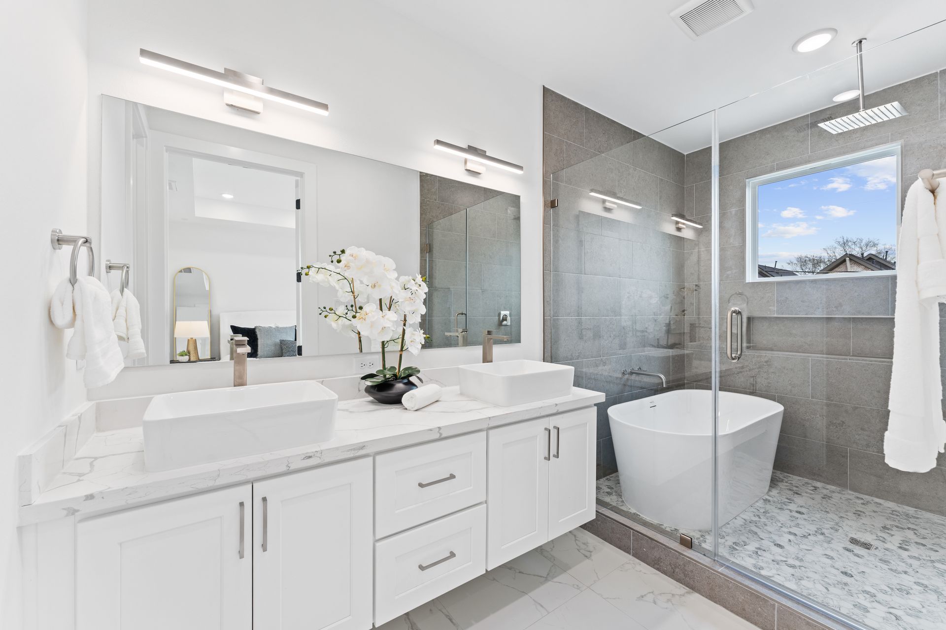 Modern white bathroom with double sinks, a soaking tub, and a walk-in shower.