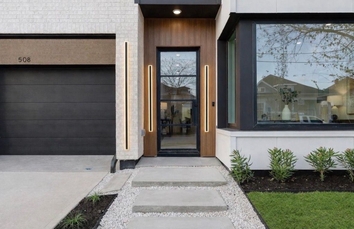 Modern front entry with wood door black trim and clean stucco facade in Houston luxury home