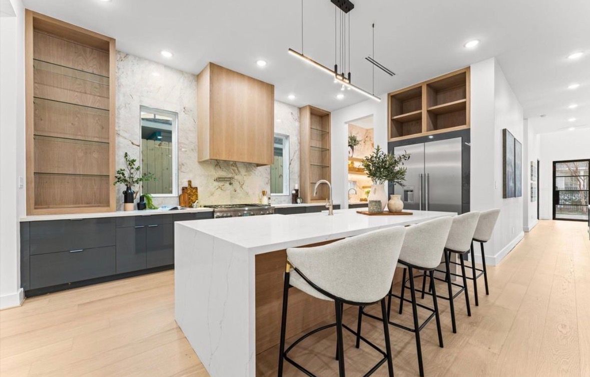 Side view of modern kitchen with custom cabinetry quartz countertops and built in appliances in Houston luxury home