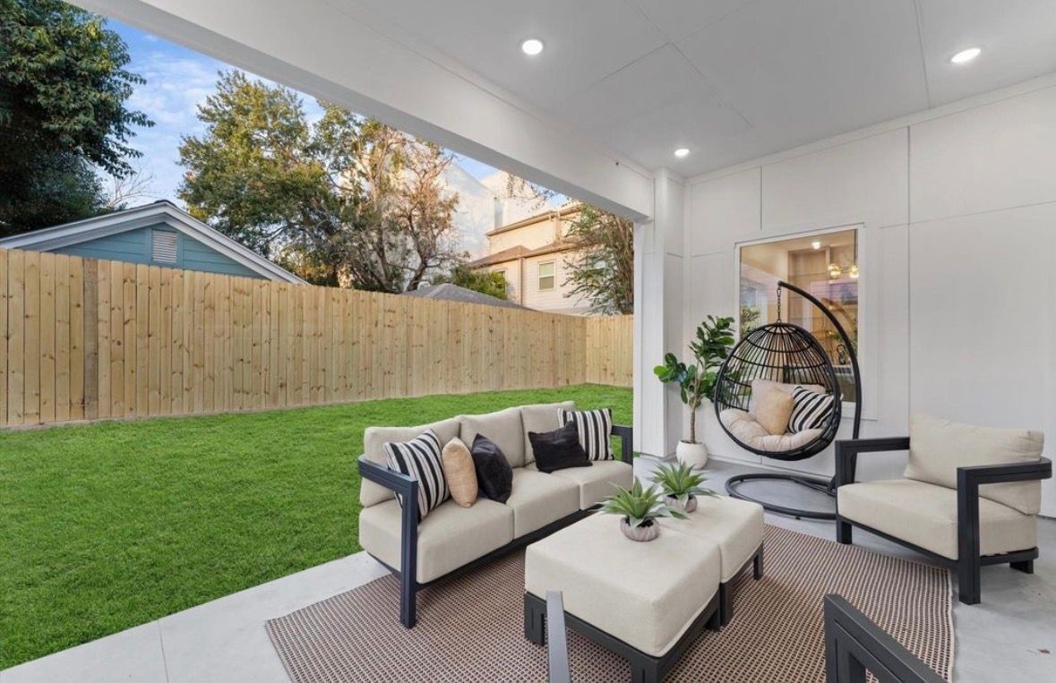 Outdoor patio seating area with modern furniture and fenced yard in Houston home