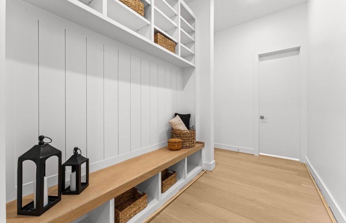 Mudroom with built in bench storage hooks and wood flooring in modern transitional home