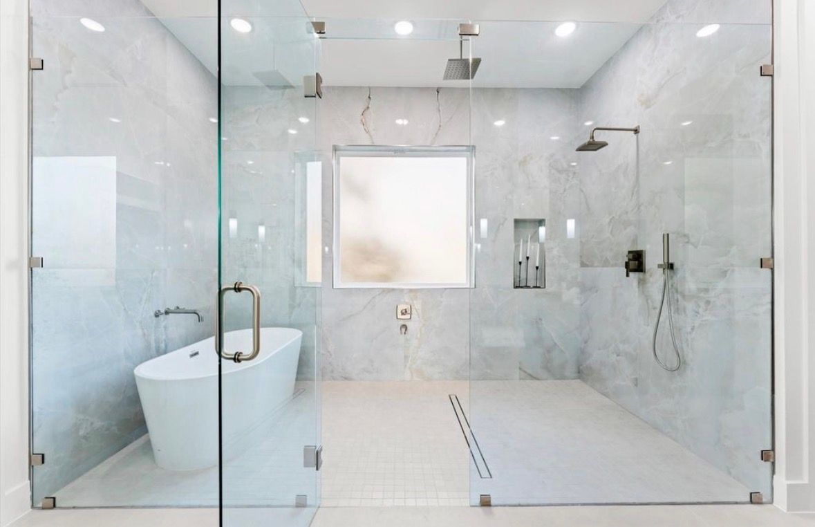 Luxury primary bathroom with freestanding tub glass shower and marble finishes