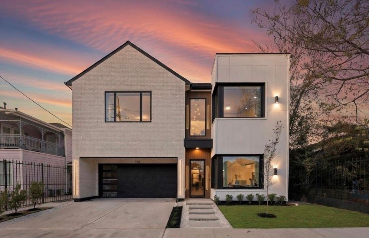 Modern transitional home exterior in Montrose Houston with stucco and black accents at dusk