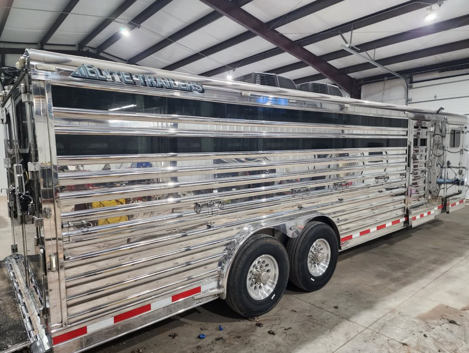 Shiny, silver livestock trailer with two axles.