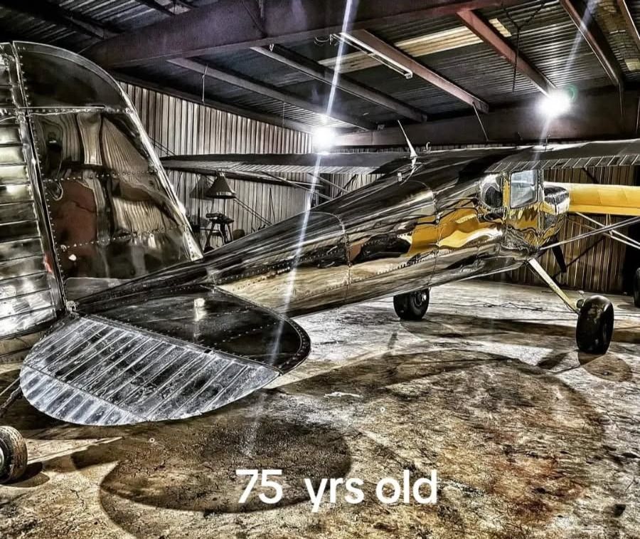 Shiny silver and yellow airplane inside a hangar, 75 years old.