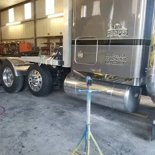 Semi-truck in a shop, silver with Hank Casper on the side.