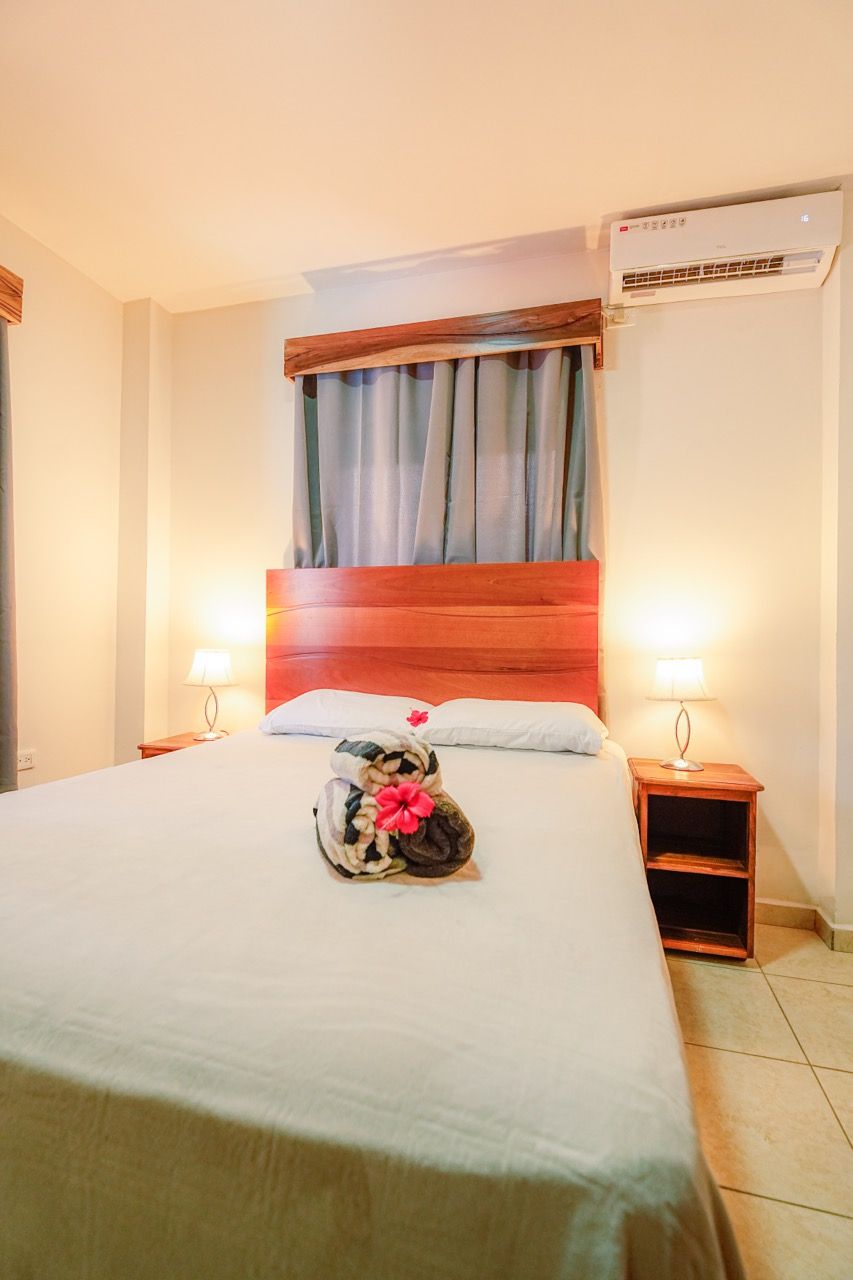 Dormitorio con cama grande, mesitas de noche y equipo de aire acondicionado.