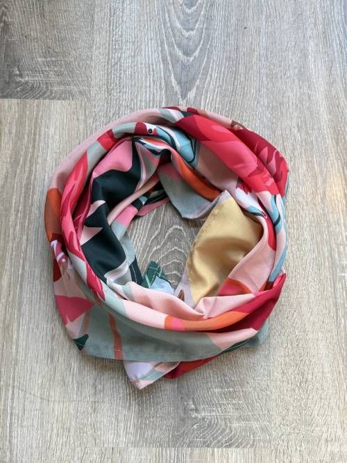 Bufanda infinita con estampado colorido sobre una superficie de madera clara.