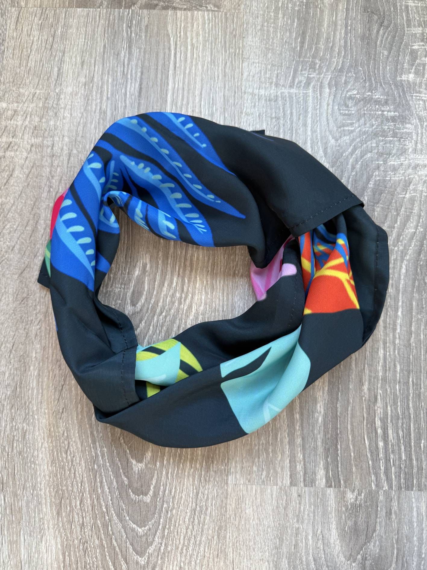 Bufanda infinita negra con estampados florales y geométricos coloridos.