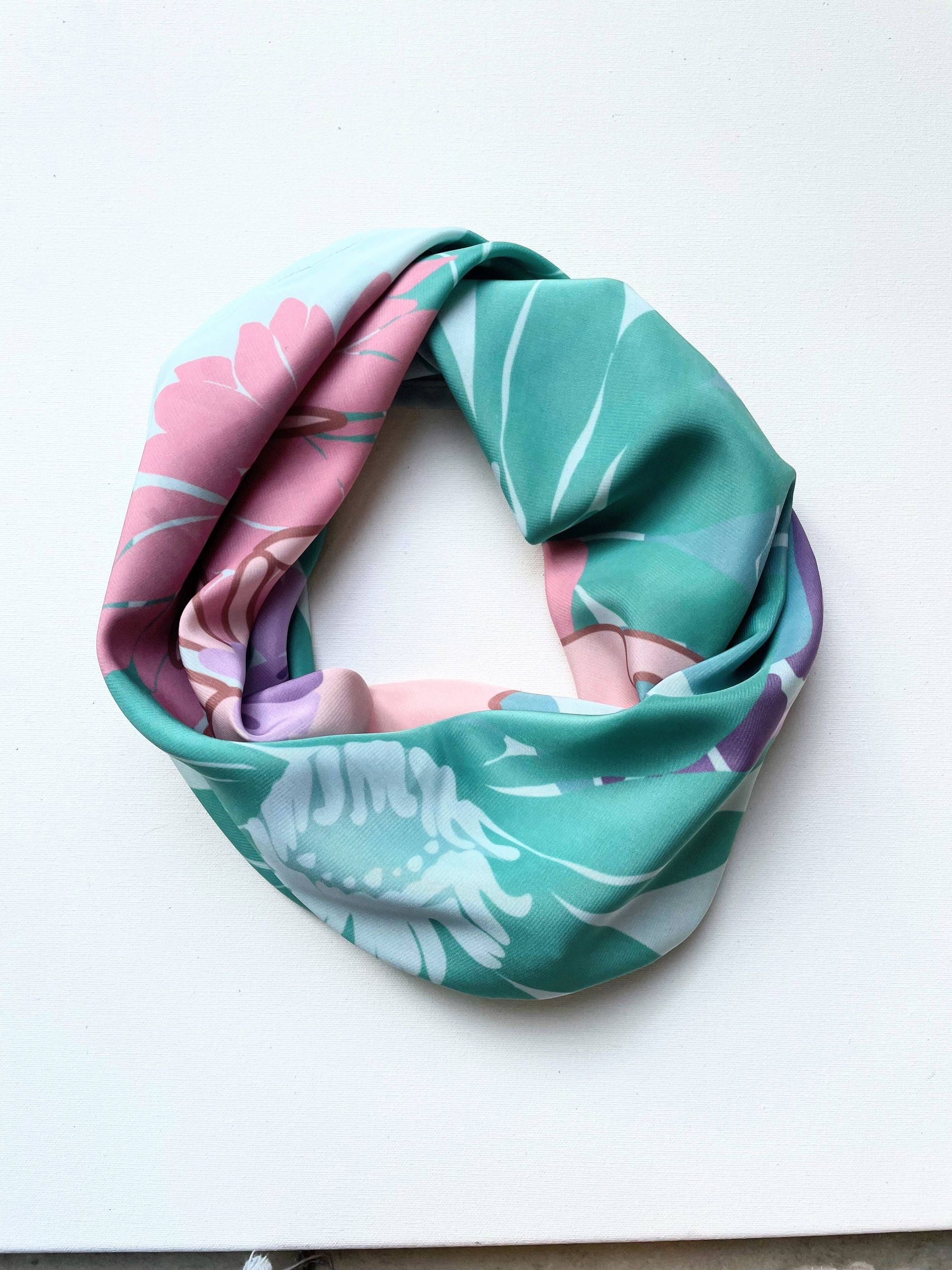 Bufanda infinita con estampado floral en tonos rosas, verdes y morados, sobre una superficie blanca.