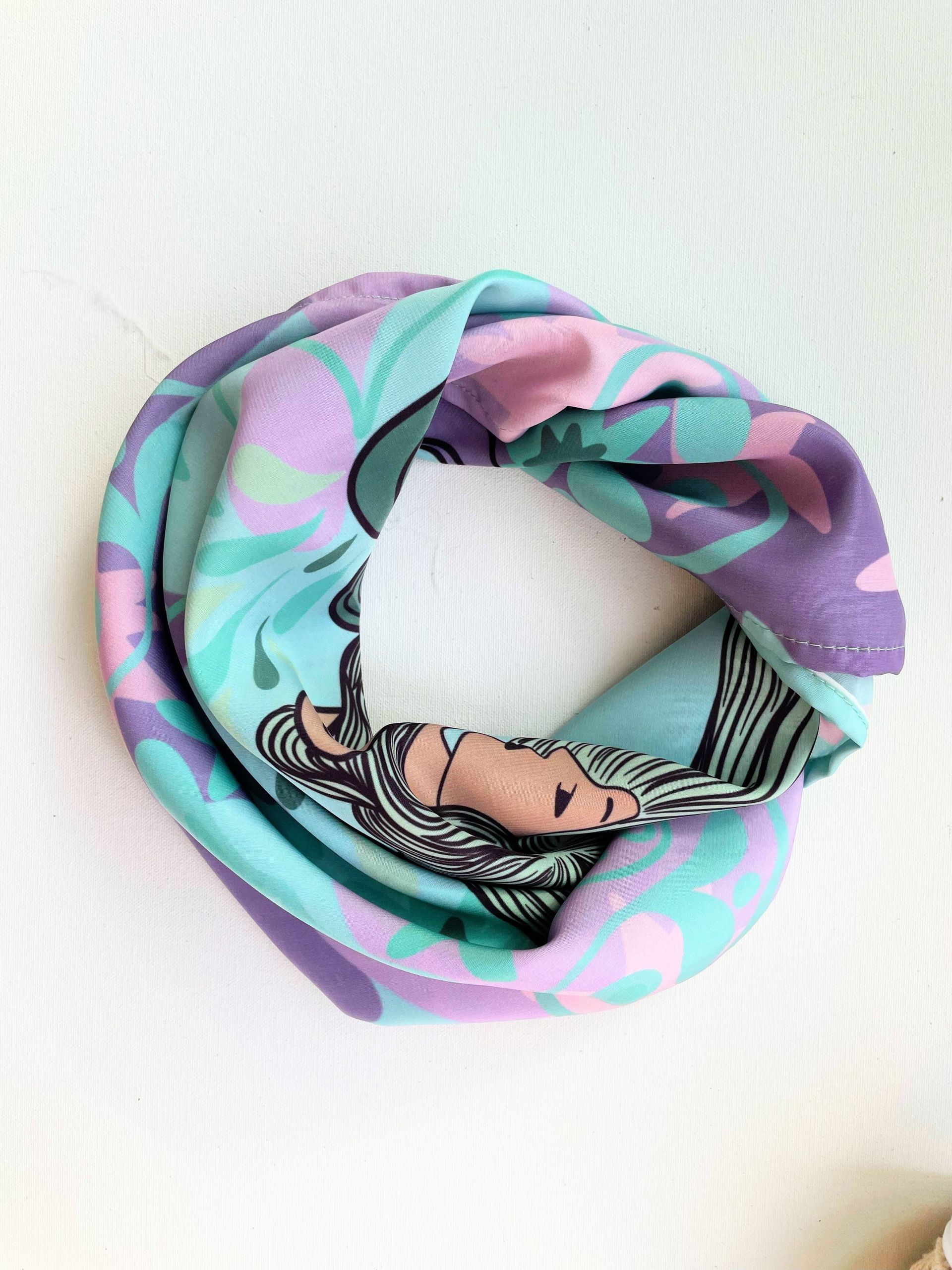 Bufanda circular con estampado floral y de rostro de mujer en tonos azules, morados y rosas.