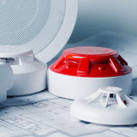 Une alarme incendie rouge et blanche est posée sur un plan.