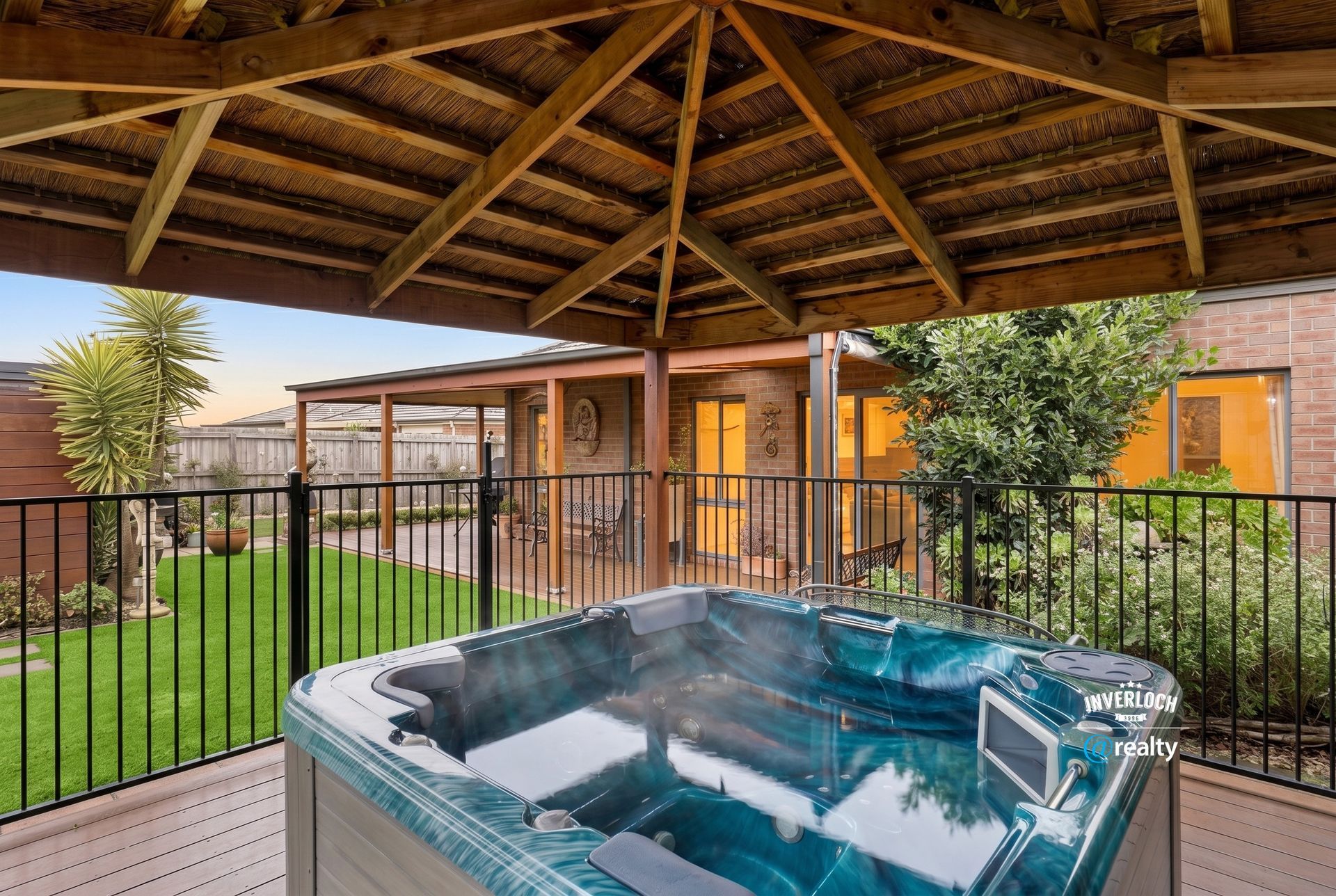 Covered patio with a hot tub overlooking a green courtyard and brick buildings