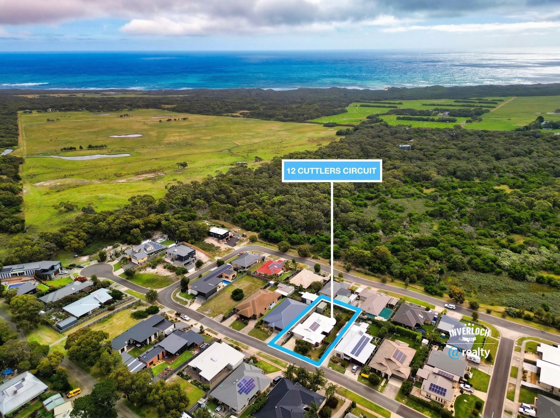 Aerial view of a residential neighborhood near the coast, with a specific house highlighted by a blue border and label.