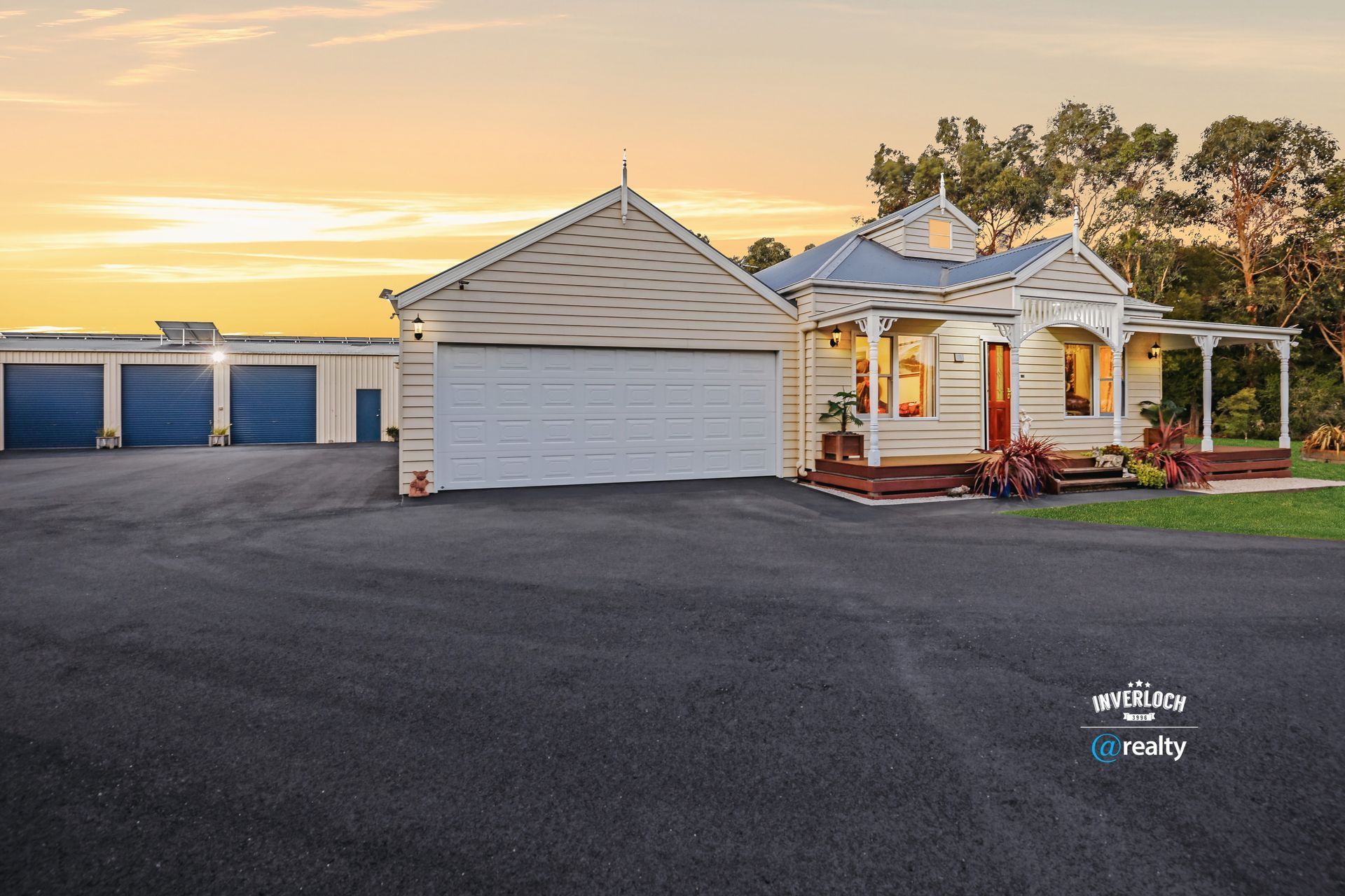A large white house with blue garage doors is for sale