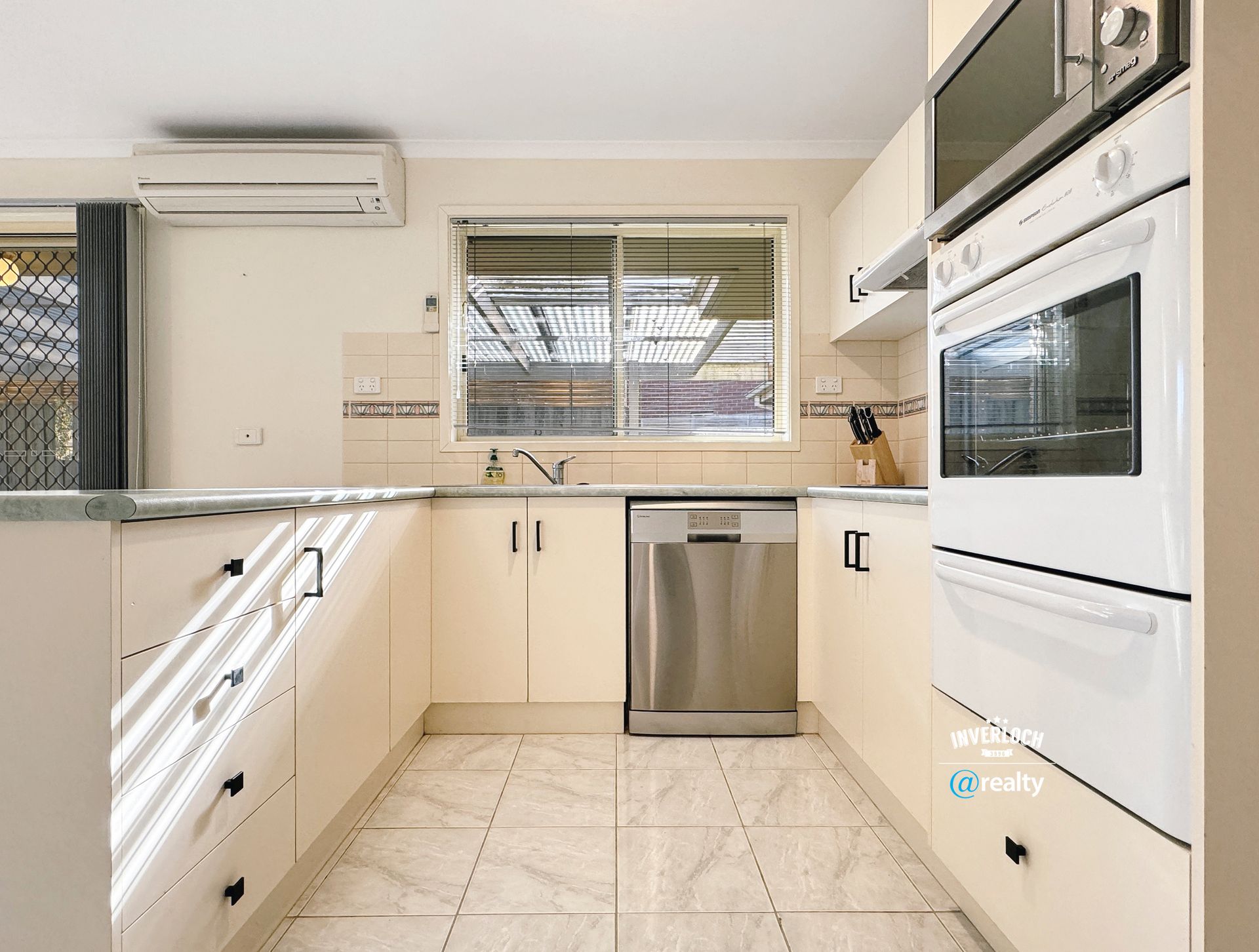A kitchen with stainless steel appliances and white cabinets.