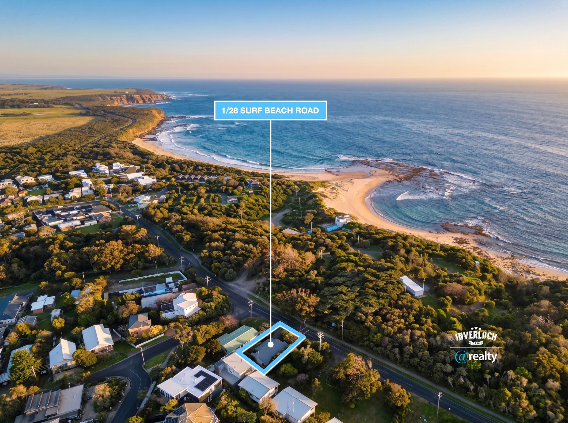 Aerial view of a coastal town with beaches, ocean waves, and sunset light over houses and greenery