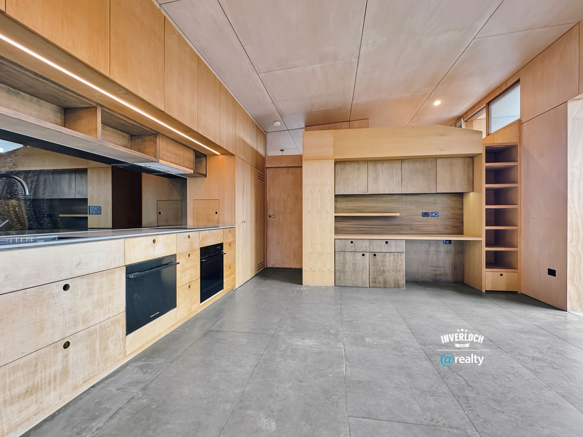 A kitchen with wooden cabinets and a concrete floor.