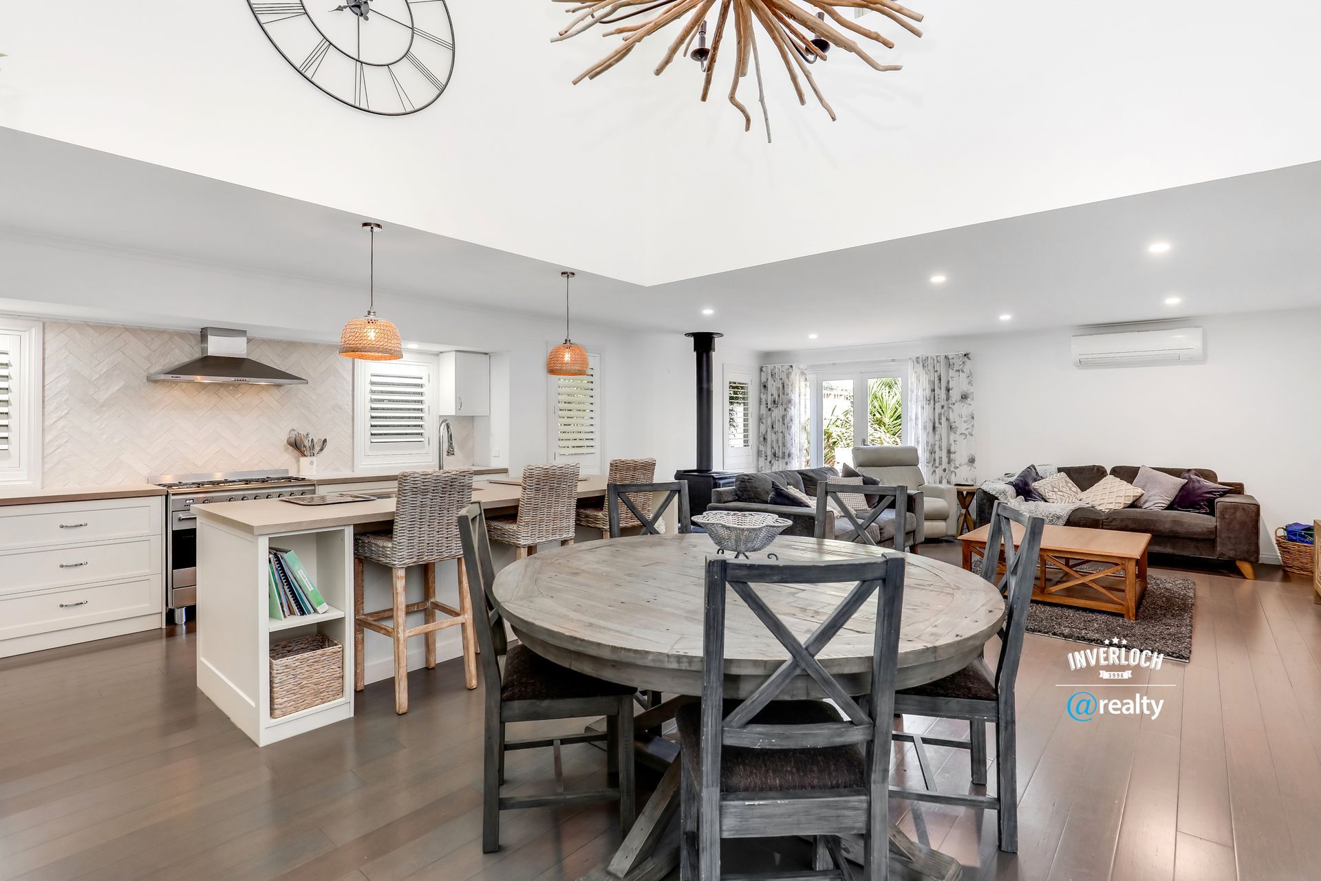 A large living room with a dining table and chairs and a clock on the ceiling.