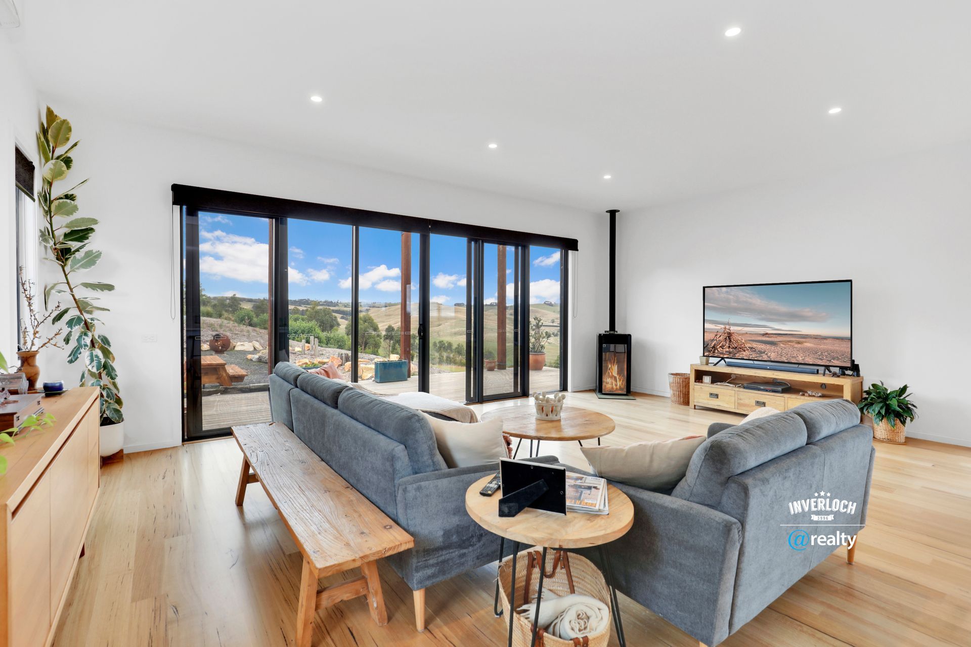 Living room with blue sofa, wooden floors, large windows, and scenic view.