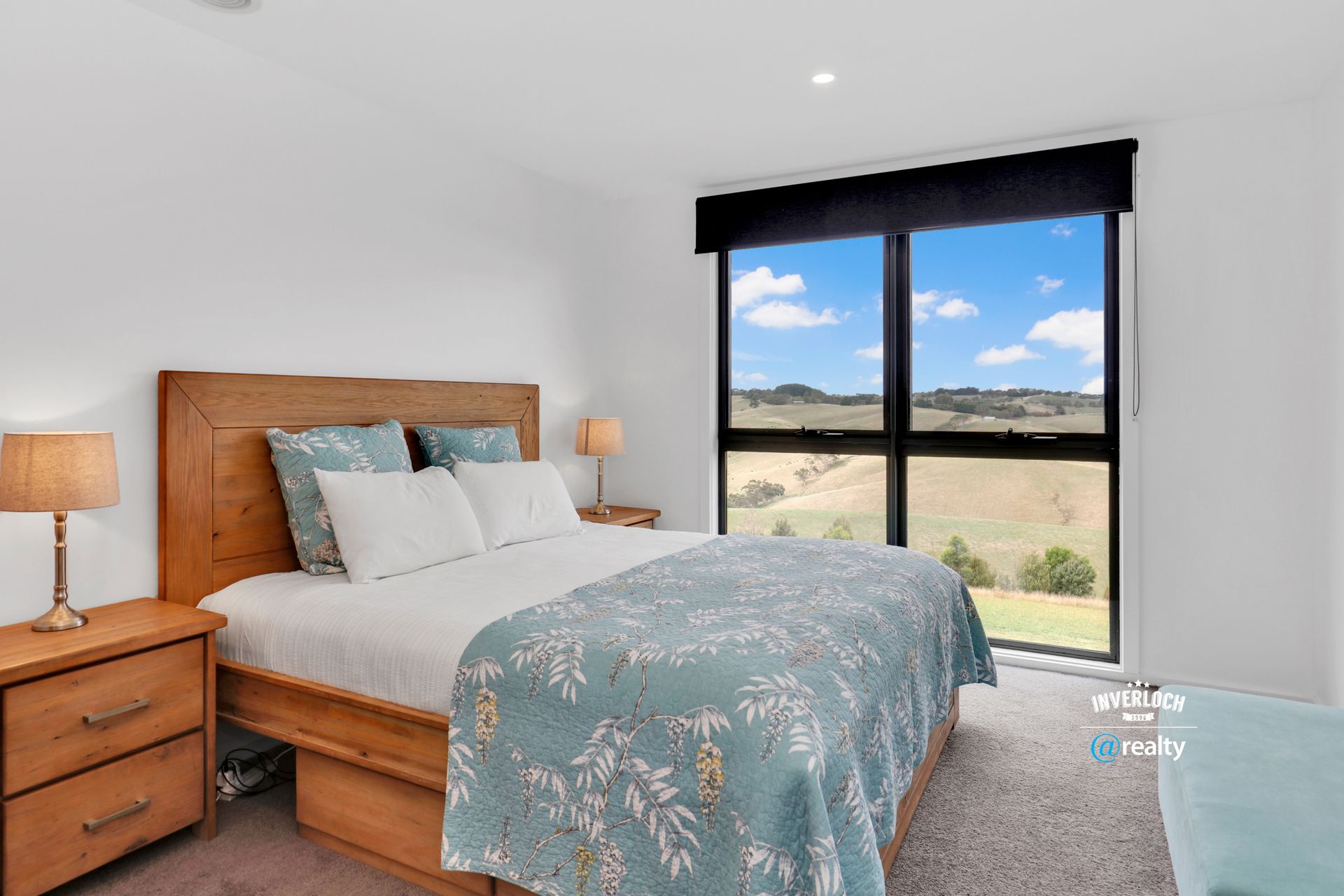 Bedroom with a bed, nightstands, and a large window offering a rural landscape view.