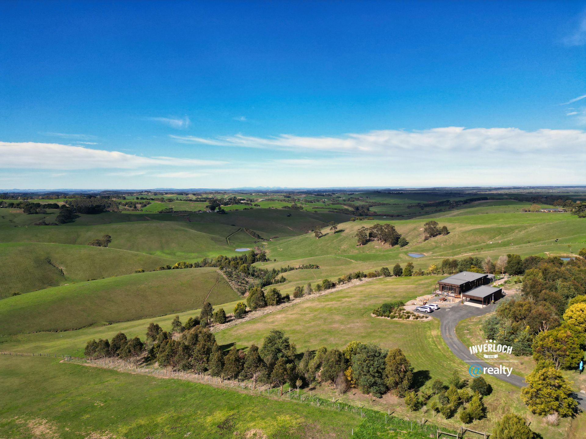Rolling green hills and a building under a clear blue sky.