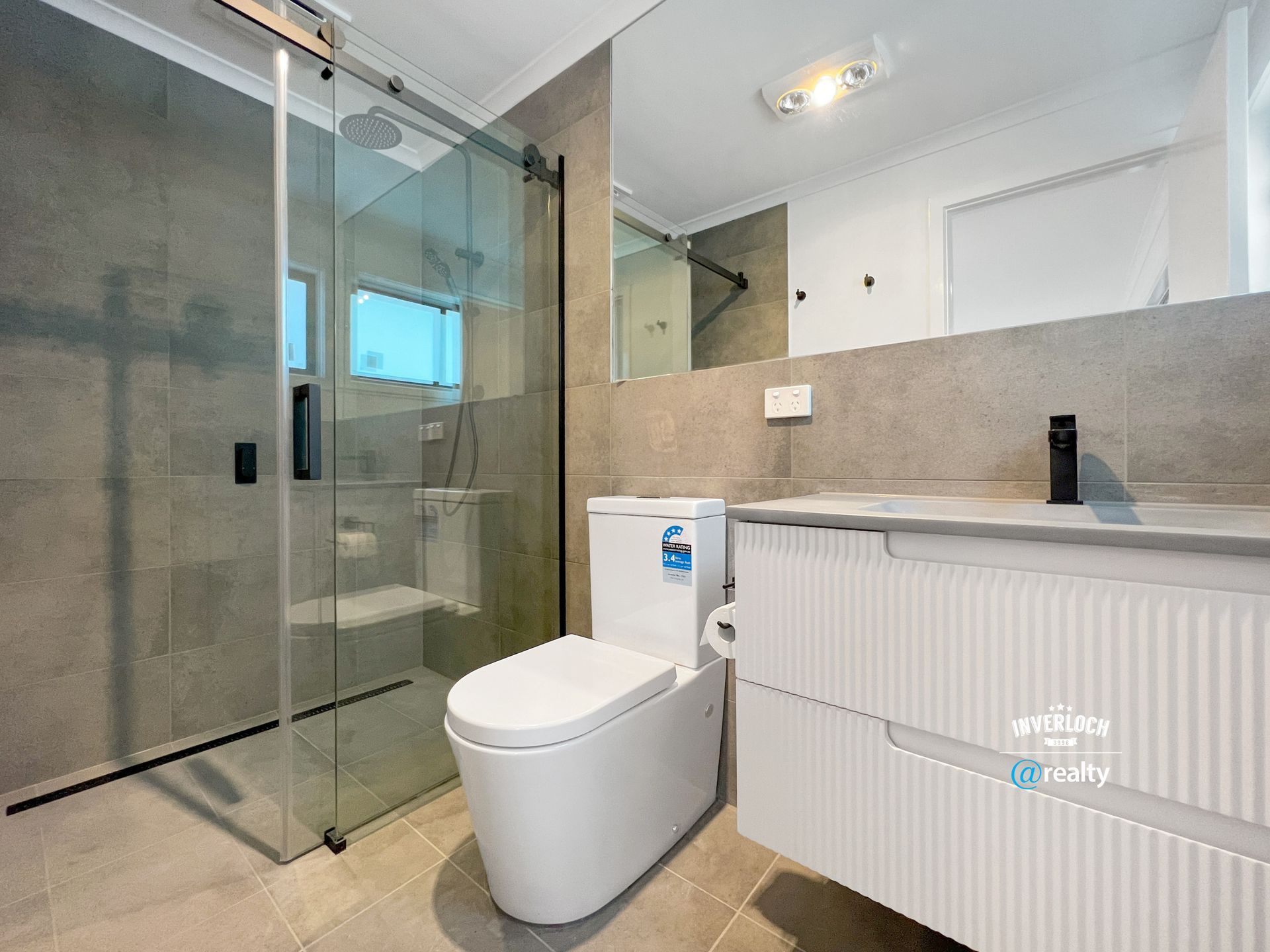 A bathroom with a toilet , sink and shower.