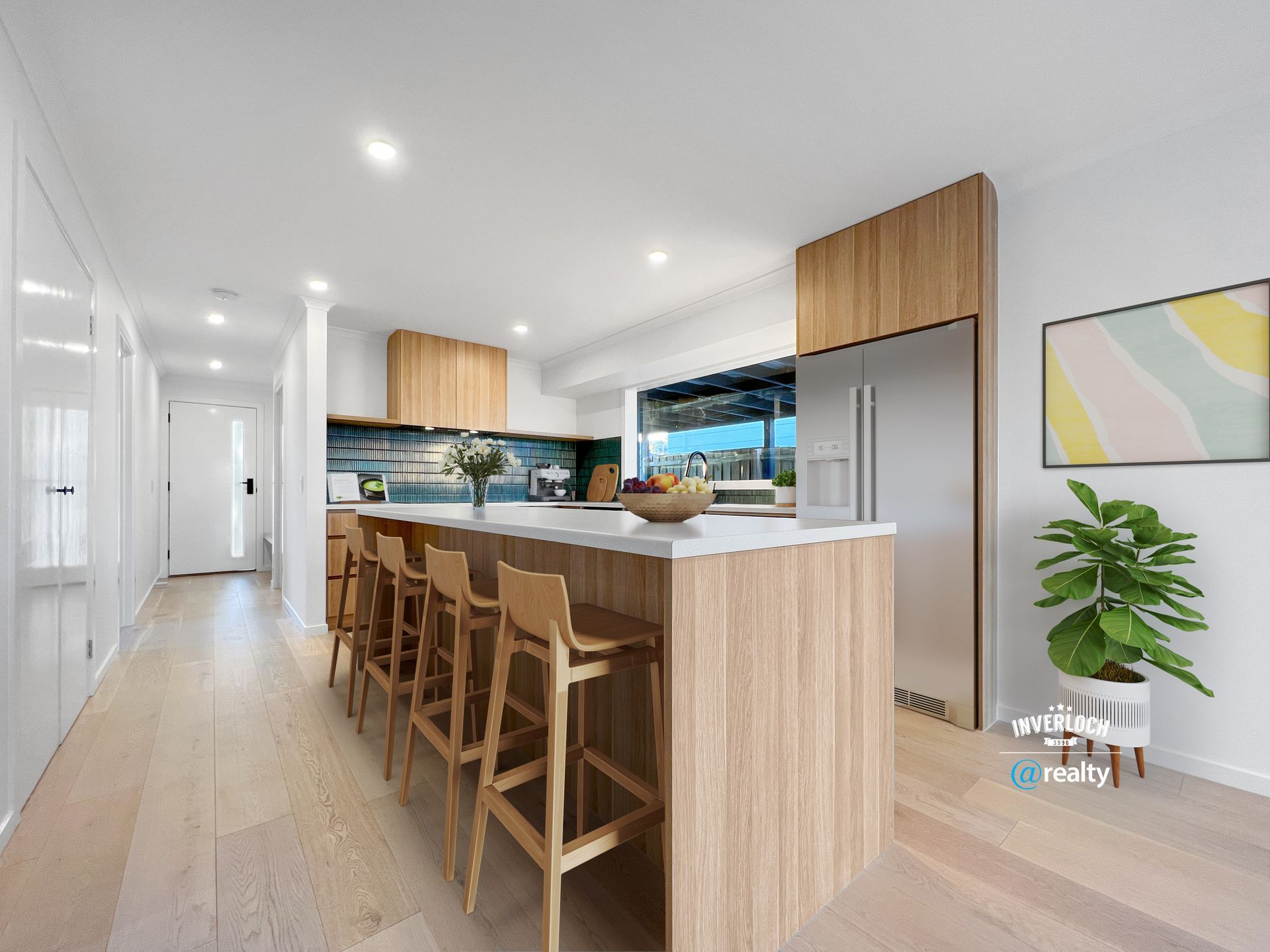 A kitchen with a large island and stools and a stainless steel refrigerator.