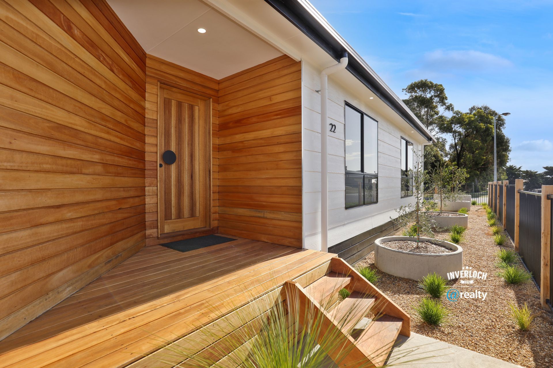 The front door of a house with wooden siding and stairs leading up to it.