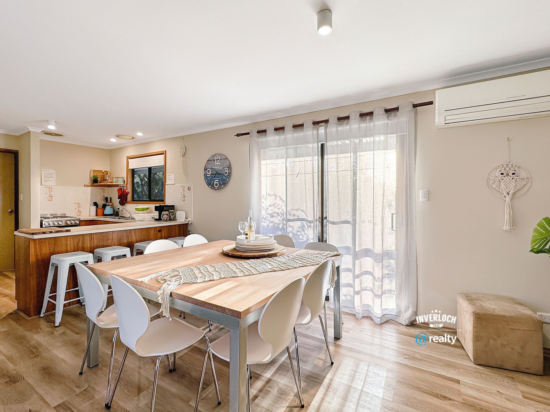 A dining room with a wooden table and white chairs.