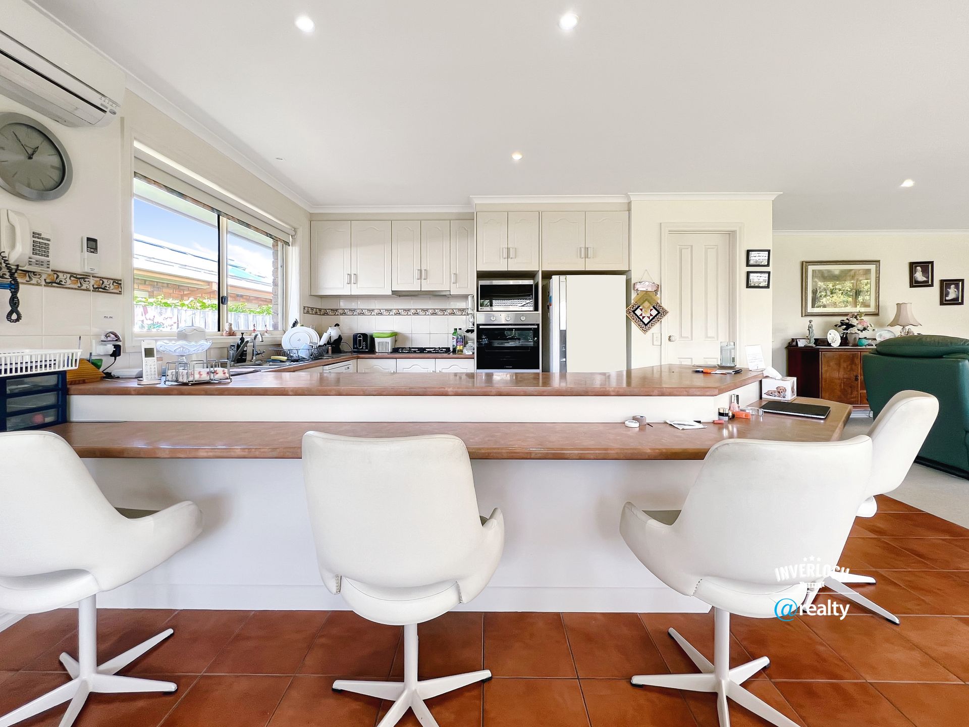 A kitchen with white chairs and a clock on the wall