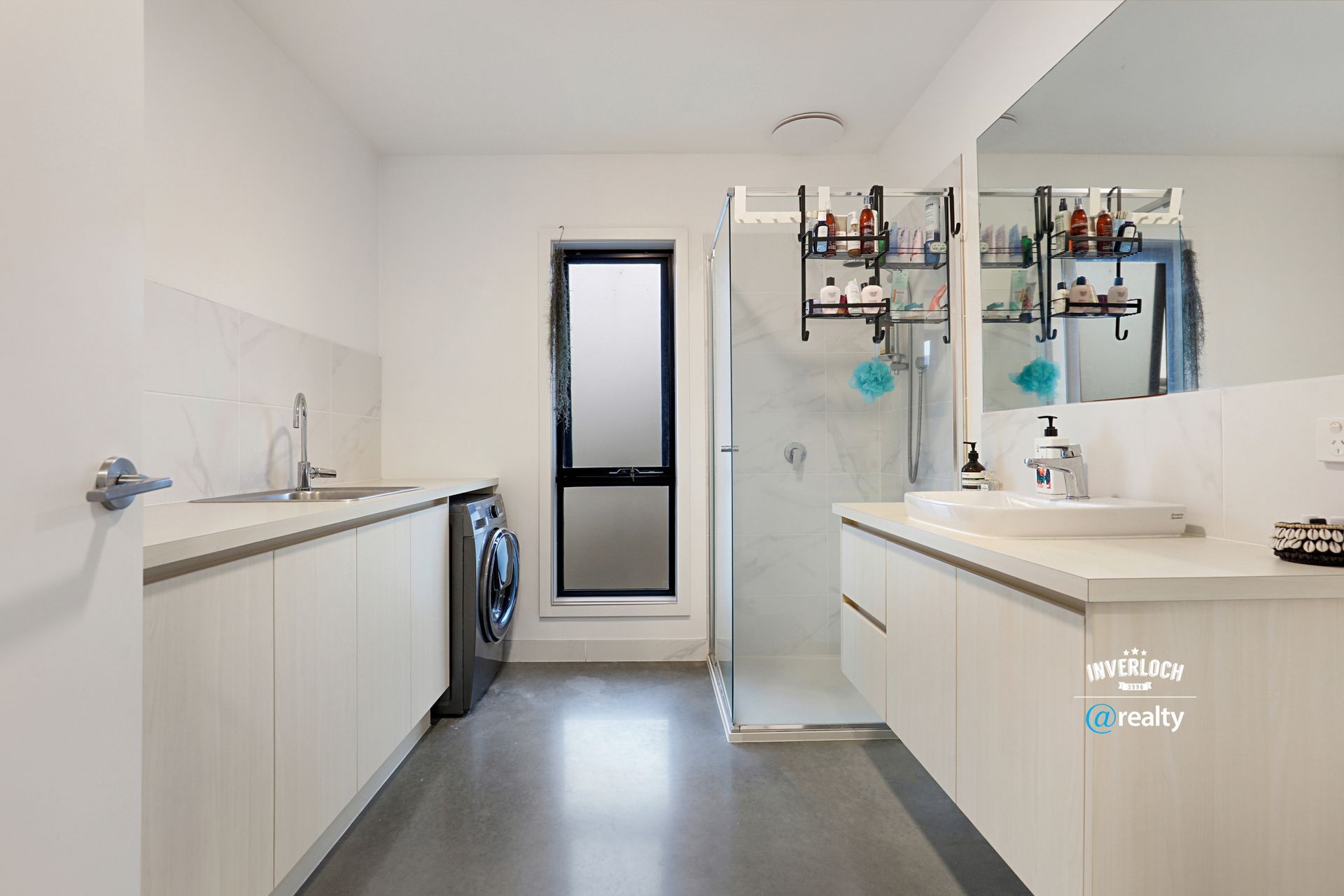A bathroom with a sink , mirror , washer and dryer.