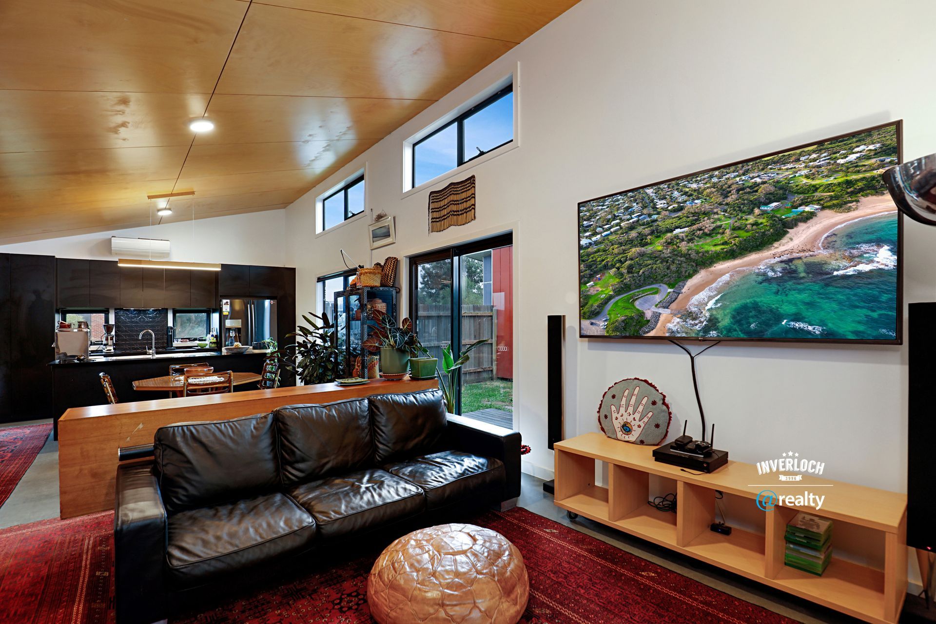 A living room with a couch and a flat screen tv on the wall.